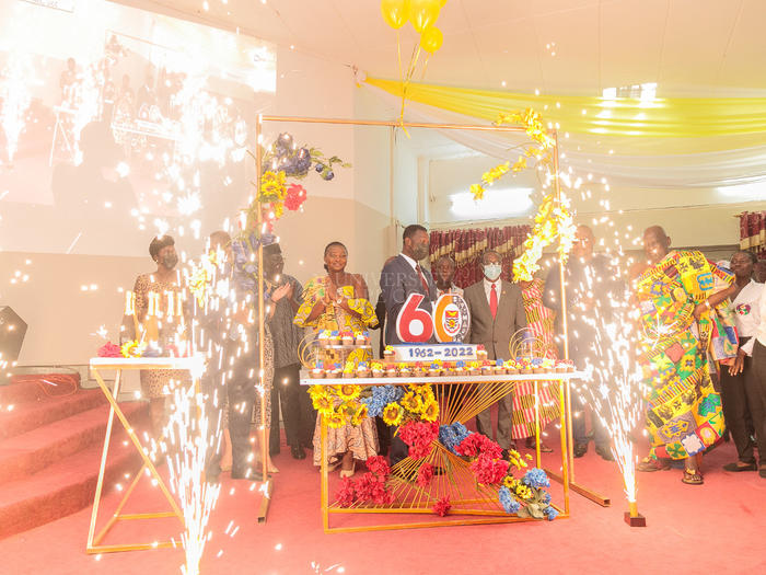 Hon. Minister of Education (middle) supported by other dignitaries at the launch to cut the anniversary cake