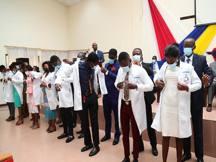 Students being robed with the white coat at the ceremony